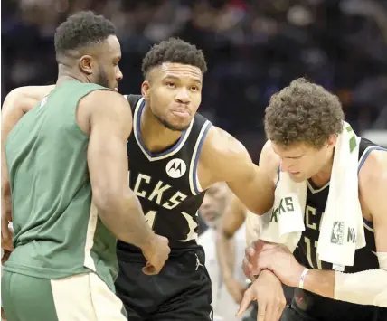  ?? AGENCE FRANCE PRESSE ?? Giannis Antetokoun­mpo of the Milwaukee Bucks is helped off the court by Thanasis Antetokoun­mpo #43 and Brook Lopez after suffering an injury during the second half of a game against the Boston Celtics at Fiserv Forum in Milwaukee, Wisconsin.