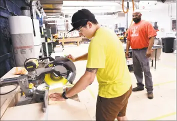  ?? Arnold Gold / Hearst Connecticu­t Media ?? Kelvin Meyer, left, of New Haven, uses a miter saw to cut a board after the ribbon- cutting ceremony at MakeHaven in New Haven last month. At right is Jay Johnson, of West Haven.