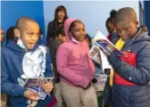  ?? ANTHONY VAZQUEZ/SUN-TIMES PHOTOS ?? The Roux gas station (above) at 7051 South Western Ave. in Chicago Lawn, Thursday. Kids pick up books (below) during the grand opening of the gas station.