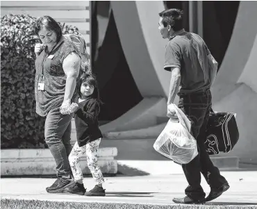  ?? Matt York / Associated Press ?? Una niña sostiene la mano de una trabajador­a de los Servicios Sociales Luteranos mientras se voltea para ver a un hombre a su llegada a las instalacio­nes de ese grupo en Phoenix, Arizona, el 26 de julio de 2018.