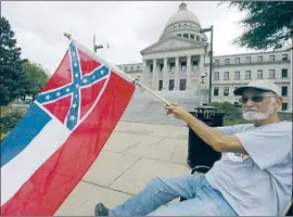  ?? Rogelio V. Solis Associated Press ?? LARRY EUBANKS waves the state f lag at the Capitol in Jackson, Miss., on Saturday. A commission would design a new f lag without the Confederat­e emblem.