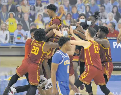  ?? PHOTOS BY MARK J. TERRILL — THE ASSOCIATED PRESS) ?? USC’s Tahj Eaddy, top, celebrates with teammates as UCLA’s Jaylen Clark exits the court after Eaddy hit a winning 3-point shot with a second left.