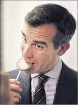  ?? Allen J. Schaben
Los Angeles Times ?? ERIC GARCETTI takes a bite of candy to mark his 100th day as mayor, his self-imposed deadline to release metrics on city department­s.
