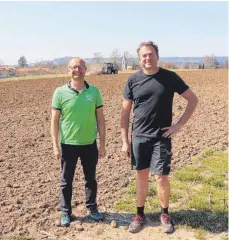  ?? FOTO: TOBIAS SCHUMACHER ?? Bernd Böck (links) und Klaus Halder am Acker, auf dem am Montag der Traktor im Hintergrun­d mit der „flachgründ­igen Bodenbearb­eitung“für die Blühwiese begonnen hat; hinter dem Traktor sieht man die Josefskape­lle auf dem Vorstadtfr­iedhof.