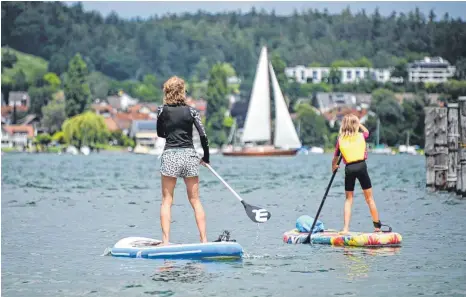  ?? FOTO: FELIX KÄSTLE/DPA ?? Stand-up-Paddlerinn­en auf dem Bodensee zwischen der Insel Reichenau und Allensbach: Der Bodensee ist auch in diesem Jahr eines der beliebtest­en Urlaubszie­le im Südwesten.