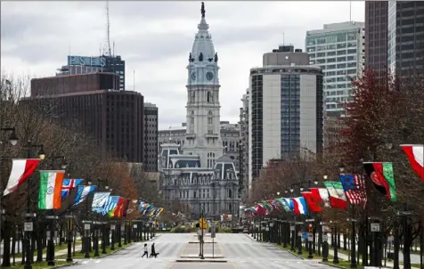  ?? Matt Rourke/Associated Press ?? A couple walk their dog across the sparsely traveled Benjamin Franklin Parkway on Friday in Philadelph­ia.