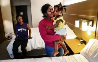  ?? JOHN TLUMACKI/GLOBE STAFF ?? Sergeline, a Haitian migrant, kissed her baby, Luna, while her son, Fritz, sat on a bed in a hotel room in Boston. They arrived from Boston Medical Center’s waiting room.