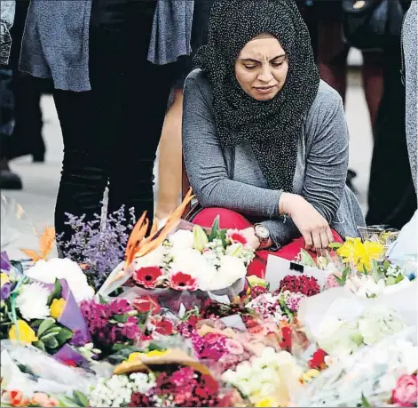  ??  ?? Dos mujeres depositan flores en homenaje a las víctimas en el lado sur del Puente de Londres