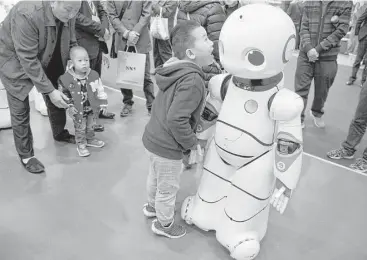  ?? Ng Han Guan / Associated Press ?? A boy shouts into the Canbot, a companion robot, displayed during the World Robot Conference in Beijing. China is showing off its robot industry as it seeks to promote more advanced technologi­es in its factories.