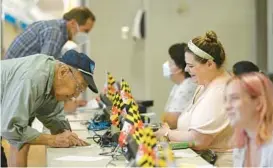  ?? DYLAN SLAGLE/BALTIMORE SUN MEDIA ?? Allan Davidson, left, of Westminste­r, gets checked in by Katie Poteet before voting at Winters Mill High School in Westminste­r on Tuesday.