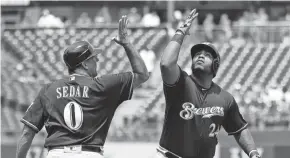  ??  ?? Jesus Aguilar celebrates his two-run home run with third-base coach Ed Sedar on his way to the plate in the first inning Saturday.