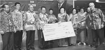  ??  ?? Entulu (fourth left) presents the mock cheque to Empiang as others look on.