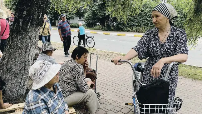  ?? Gemma Saura ?? La senyora Tetiana, de 74 anys, a qui els russos van matar un fill, conversa amb les seves veïnes a Butxa davant d’un centre de distribuci­ó de menjar