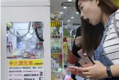  ??  ?? A woman reacting while operating a claw crane machine at a store in Taipei. As Taiwan’s economy stagnates, claw crane arcades where customers lower a grabber to try to pick up a prize from a glass box are booming as affordable entertainm­ent, while operators see them as a way to make a fast buck. – AFP photo