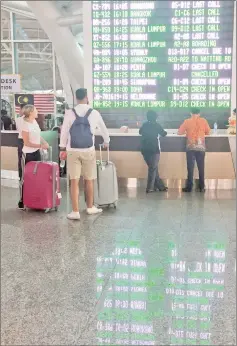  ??  ?? Internatio­nal passengers are seen near the flight informatio­n board at Ngurah Rai Bali Internatio­nal Airport, Kuta, Bali. — Reuters photo