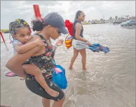  ?? Stuart Villanueva Th e Associated P ress ?? Stacey Young gives her daughter, Kylee Potts, a piggyback ride Saturday across the flooding Stewart Beach parking lot in Galveston, Texas.