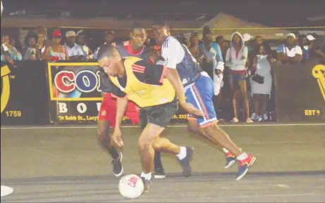  ??  ?? Deon Charter (yellow) of Hustlers trying to evade two players from Bagotstown Ballers during their eliminatio­n match in the third annual Guinness ‘Greatest of the Streets’ West Demerara/East Bank Demerara zone at the Pouderoyen Tarmac Friday night....