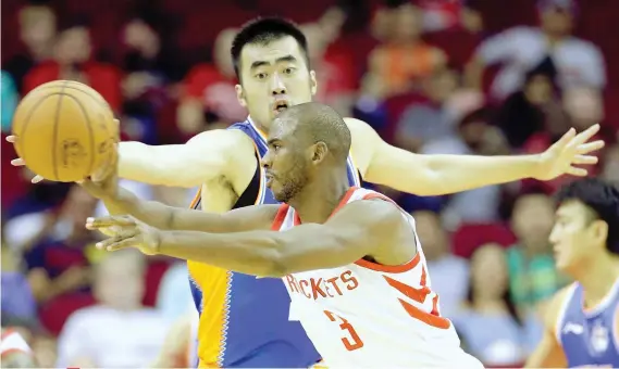  ?? AP FOTO ?? DEBUT. Shanghai Sharks center Zhang Zhaoxu (No. 23) tries to defend against the pass by Houston Rockets guard Chris Paul (No. 3) in the first half of an NBA exhibition basketball game. Paul debuts for the Rockets with 11 points, 12 assists and four...