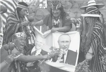  ?? GUADALUPE PARDO/AP ?? Predicting 2022: Shamans hold photos of U.S. President Joe Biden and Russian President Vladimir Putin on Wednesday in Lima, Peru. As part of a year-end ritual, the shamans predict political and social issues for the coming year. They also asked that
the COVID-19 pandemic end and that world leaders be cleansed in order to make wise decisions in 2022.