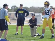 ?? TIFFANY TOMPKINS, AP ?? Michigan coach Jim Harbaugh, kneeling, is a strong proponent of satellite camps, which were reinstated Thursday.