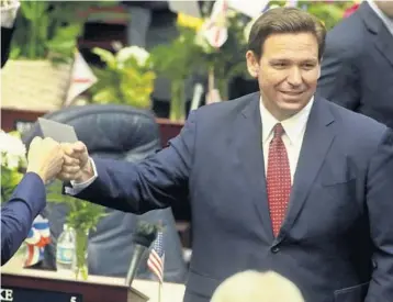  ?? PHIL SEARS/AP ?? A maskless Gov. Ron DeSantis fist-bumps with legislator­s as he enters the House of Representa­tives on March 1 before his State of the State address at the Capitol in Tallahasse­e.