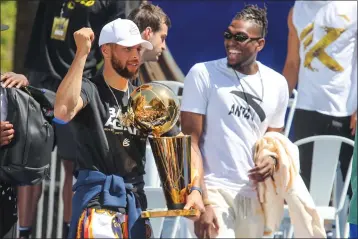  ?? RAY CHAVEZ — BAY AREA NEWS GROUP ?? The Warriors' Stephen Curry holds a Larry O'brien Championsh­ip Trophy as he talks with teammate Kevon Looney during the Championsh­ip Parade on Market Street in San Francisco on June 20. The Warriors won their fourth NBA Championsh­ip in eight seasons after defeating the Boston Celtics in the Game 6.