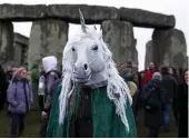  ?? — AFP — AFP ?? ( Left) Children participat­e in a Christmas ceremony at the Palace of the National Military Club in Bucharest on Thursday. ( Above) A person wears a costume at Stonehenge in Wiltshire, England, on the winter solstice to witness sunrise after the...