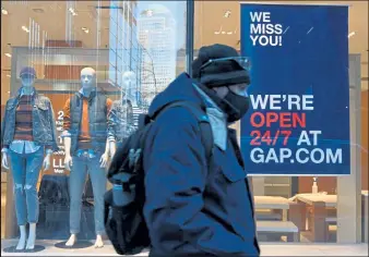  ?? Angela Weiss / Getty Images ?? A man walks past a store on Jan. 12 in New York City. Bouncing back from months of retrenchme­nt, America’s consumers stepped up their spending by a solid 2.4% in January, the sharpest increase in seven months and a sign that the economy may be poised to sustain a recovery from the pandemic recession.