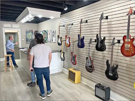  ?? (Rhett Gentry/Banner-News) ?? Kevin Barker speaks to guests as they peruse his new music store, Vintage Sound. Set to open in May, Barker said that the store will host a variety of musical instrument­s and equipment.