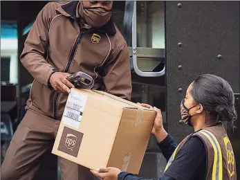  ?? Contribute­d photo ?? A UPS driver and a driver’s helper unload a package.