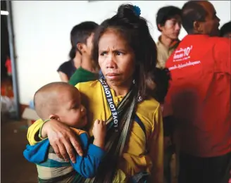  ?? Associated Press photo ?? A woman carrying her baby waits at a shelter in Paksong town, Champasak province, Laos on Wednesday.