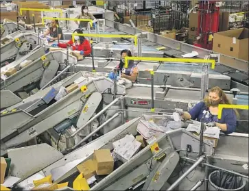  ?? Irfan Khan Los Angeles Times ?? MAIL CLERKS work at automated sorters at a U.S. Postal Service facility in City of Industry. The service has seen package volume surge during the pandemic, an issue exacerbate­d by staff shortages and policy changes.