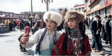  ?? ?? Women take selfies on Barkhor Street in Lhasa, capital of Xizang Autonomous Region, on February 11