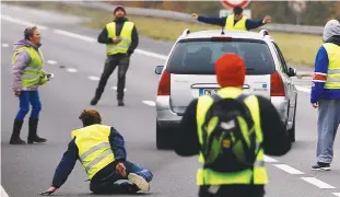  ??  ?? A car drives through a blockade as protesters wearing yellow vests try to block a road in Donges on Saturday.