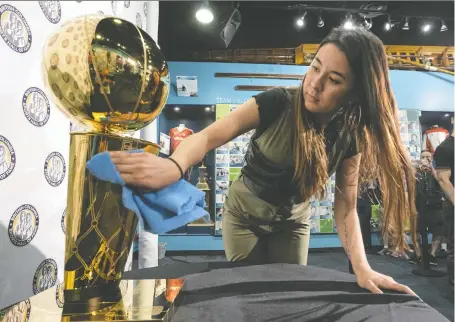  ?? RICHARD LAM FILES ?? Tenneya Martin gives the Larry O'brien NBA Championsh­ip Trophy a polish before a public showing in Vancouver in 2019.