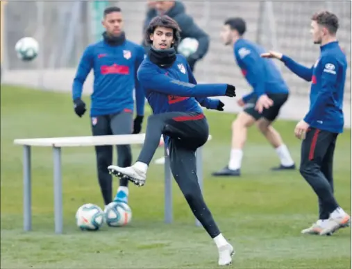  ??  ?? João Félix patea un balón en la sesión de entrenamie­nto del Atlético ayer en el Cerro del Espino. Detrás, Trippier y Lodi, también de los ‘sanos’.