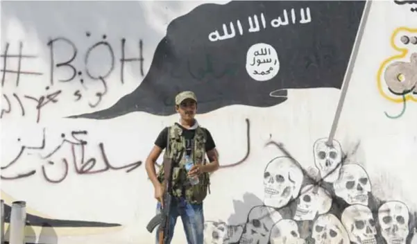  ?? |GETTY IMAGES ?? Un combatient­e de la coalición rebelde siria frente a un mural del Estado Islámico en Raqqa.