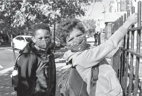  ?? ULYSSES MUÑOZ/BALTIMORE SUN ?? Caleb Webb, 8, and Isaiah Chappell, 6, get ready to go home after Patterson Park Public Charter School let out for the day on Wednesday.“I wish,”Caleb said,“they had a vaccine for kids so that we didn’t all have to wear masks and can see our actual faces.”