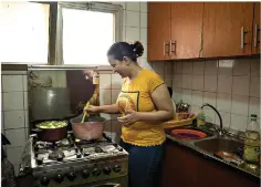  ??  ?? Fatma Youssef, a volunteer with a program that sends meals to quarantine­d coronaviru­s patients, cooks a meal for a family July 11 in her apartment in Cairo, Egypt. (AP Photo/ Nariman El-Mofty)