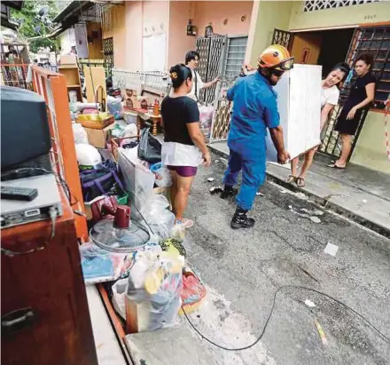  ??  ?? Anggota Pasukan Pertahanan Awam turut membantu mangsa mengangkat barang untuk berpindah ke kawasan selamat dalam kejadian lima buah rumah mengalami rekahan besar dan mendapan tanah.