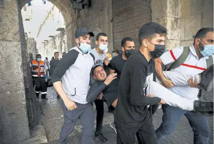  ?? By Josef Federman and Fares Akram Oded Balilty, The Associated Press ?? Palestinia­ns evacuate a wounded protester during clashes with Israeli security forces Monday at Jerusalem’s Lions Gate near the Al-Aqsa mosque, or Temple Mount, a flashpoint holy site in the city.