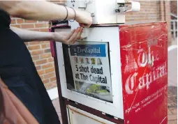  ??  ?? A woman buys a copy of the Capital Gazette from a newspaper box on Friday in Annapolis, Maryland.