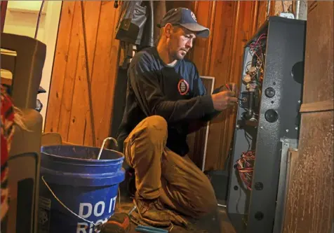  ?? Steve Mellon/Post-Gazette ?? Scott Fedak, of J&A HVAC of South Park, installs a furnace Friday at the North Braddock home of Raymond and Stacey Webb, two veterans struggling because of health issues.