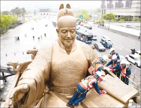  ?? ?? Workers conduct annual cleaning operation on the bronze statue of King Sejong in Seoul, South Korea on April 16. (Xinhua)