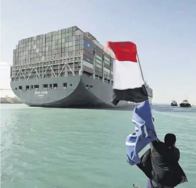  ?? EUROPA PRESS ?? Un hombre ondea una bandera de Egipto ante el mercante que encalló en el canal de Suez.