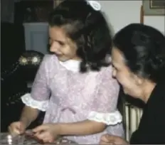  ??  ?? Gina D’Ascenzo (now Carlos) unwraps her Christmas present with her grandmothe­r, Irma D’Ascenzo, looking on. This is a clip from the D’Ascenzo home movies.