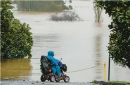  ?? MARK BAKER/AP ?? A woman looks over inundated farmland Monday near Sydney as Australia’s largest city braces for its fourth and possibly worst round of flooding in 18 months.