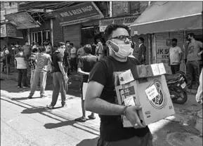  ??  ?? A customer carries alcohol after purchasing from a wine shop at Chander Nagar in East Delhi. (PTI)