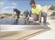  ?? Erik Trautmann / Hearst Connecticu­t Media file photo ?? ENCON employees including C.J. Pappas, left, install solar panels on the roof of the Paul Miller Nissan dealership in Fairfield in 2018.