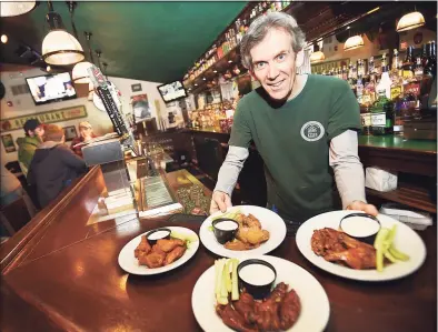  ?? Hearst Connecticu­t Media file photo ?? Kevin Canel displays a sample of buffalo, garlic parmesan, chipotle and raspberry bourbon wings at Archie Moore's Bar & Restaurant at 15 Factory Lane in Milford.